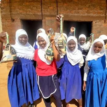 SAG Kit Distribution image showing Happy Hours Primary School girls receiving 221 kits in Bombo, Uganda on Sep 17, 2025